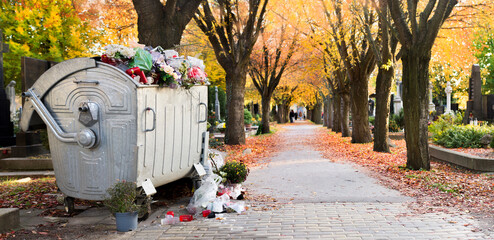 Waste bin among Trees in bright fall colors in the cemetery. Graves and golden maple leaves on All Souls Day,