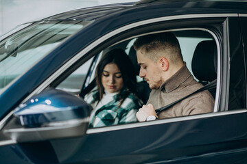 Young couple sitting in car in a car showroom