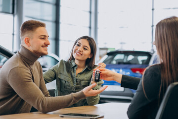 Fototapeta premium Young couple talking to a sales person in a car showroom