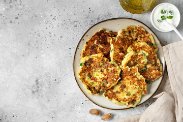 Homemade potato pancakes with cottage cheese and green onions in a ceramic plate on a bright kitchen table close-up. A traditional dish of European cuisine made of vegetables	