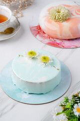 Fototapeta na wymiar Trendy mousse cake with mirror glaze decorated. Modern european desserts at white marmer stone background.
