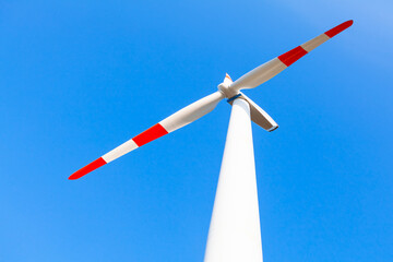 Windmill red and white blades . Wind turbine against blue sky 