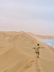 Fototapeta na wymiar person walking on the sand dunes in the sandwich harbor in Namibia 