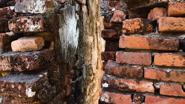 Ruins of old threadbare brick wall. Crack in the wall. Camera slowly moving upwards.