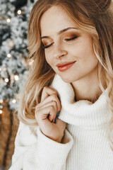 Happy woman by the christmas tree.