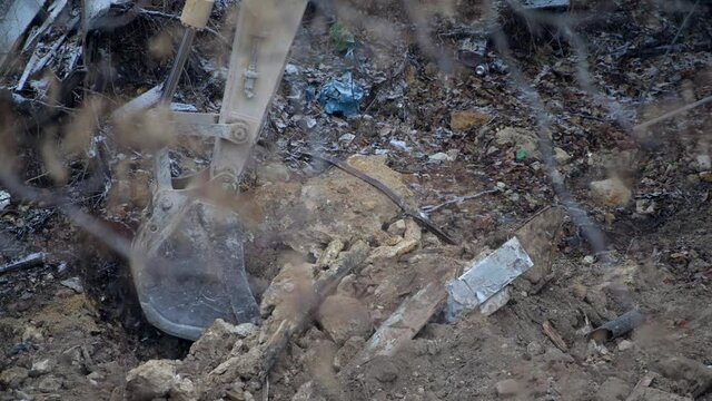 Escavator digs the frozen ground at snowfall. Deconstruction of living old house at country village at winter. Urban Renewal 4k high quality cinematic video
