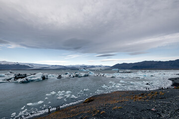 wide angle picture of Jökulsárlón lake with glacier icebergs in the lake and on the shore moody clouds
