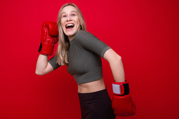 Sporty young woman in red boxing gloves is fooling around