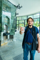 A man gives mineral thermal water in the disposable cup at the pump-room, close-up