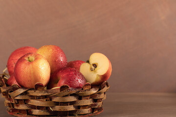 A vase of red apples on a uniform brown background. Wicker basket with harvest fruits