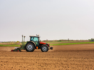 Tractor drilling seeding crops at farm field. Agricultural activity.