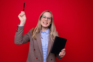 Portrait of a young woman with a diary and a pen on a red background