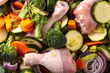 Raw vegetables with chicken drumsticks.