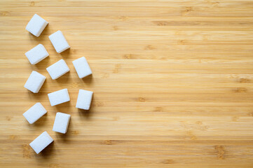 Sugar cubes on a wooden background. Top view, copy space. Diabetes control concept.