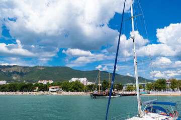 Two yachts without sails at sea and white clouds against blue sky.