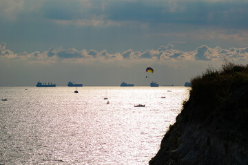 Boats and ships at sea and parachutist on the background of a beautiful sky.