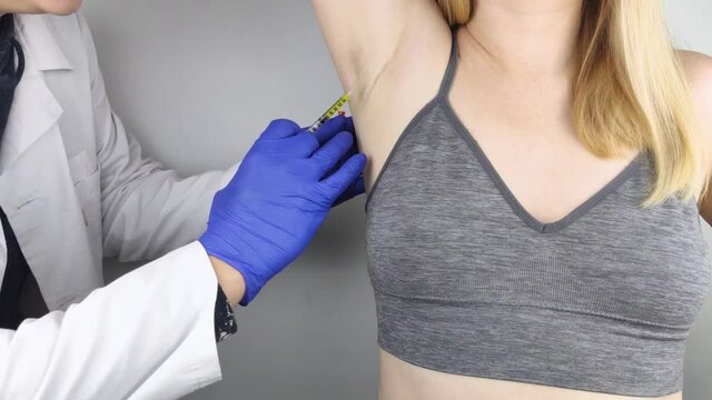 Woman receiving botulinum toxin injection in armpit as treatment of hyperhidrosis in clinic. Treatment of problems with increased sweating, anhidrosis, or malfunctioning glands. Cosmetology