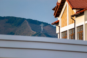 House and cross on the mountain against the background of the sky.