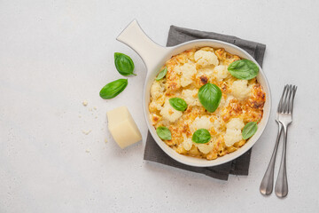 Mac and cheese with cauliflower. Baked pasta with cheese and cabbage in ceramic pot on white background. American cuisine concept
