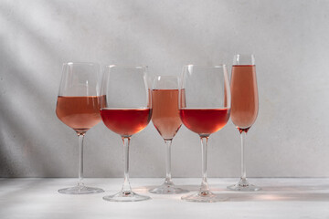 Set of rose wine or champagne in variety of glasses on white background with shadows. Romantic party, holiday, vacation concept