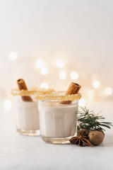 Eggnog with cinnamon and nutmeg for winter holidays. Christmas traditional eggnog in glasses on white background with garland