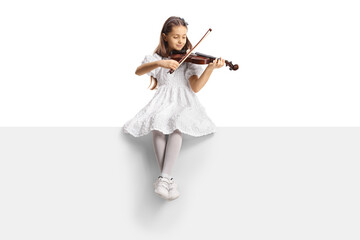 Full length portrait of a girl in a white dress sitting on a blank panel and playing a violin - obrazy, fototapety, plakaty