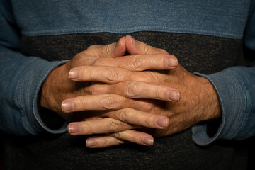 Fototapeta premium Man with hands clasped together, close up.