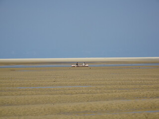 Fototapeta na wymiar [Madagascar] A small wooden boat crossing the shallow waters of the tide (Betania village, Morondava)