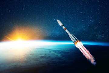 space rocket flies in the starry sky over the amazing blue planet earth and yellow sunset....