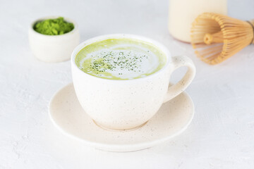 Vegan tea matcha latte with coconut milk and hemp seeds in a mug on a light background.