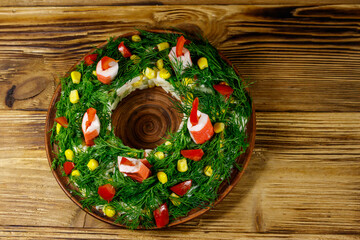 Salad Christmas wreath on a wooden table. Top view