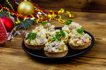 Traditional Russian festive salad Olivier in tartlets and Christmas decorations on wooden table