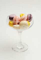 Mini colorful french macarons in a martini glass on white background. Holiday aesthetic