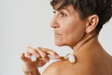 Mature half-naked woman massaging her skin with jade roller