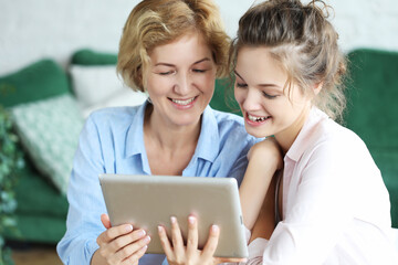 lifestyle, technology and people concept: mother and adult daughter using tablet computer at home