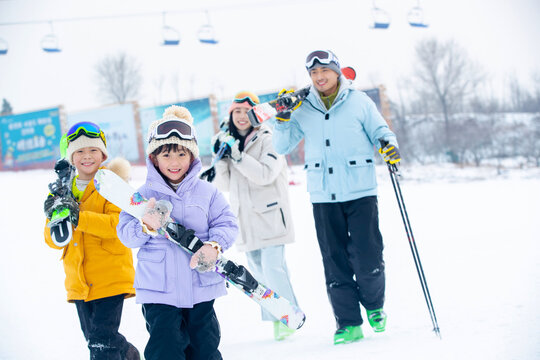 Young parents and children ski and play in ski resort