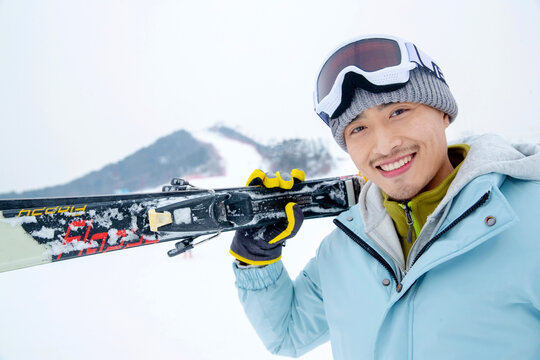the potrait of a Young man to hold the skis standing in the snow
