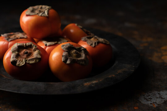 Persimmons in black weathered bowl