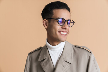 Young middle eastern man in eyeglasses smiling and looking aside