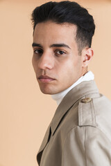 Young middle eastern man wearing coat posing and looking at camera
