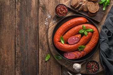 Smoked Sausage with fresh basil, spice sauce on a wooden background.