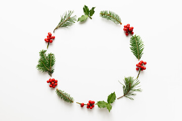 Christmas round frame made from holly berries and green twigs.