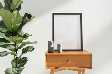 Mockup picture frame near houseplant on side table with drawer