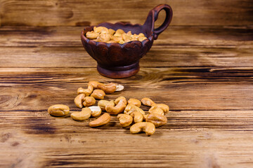 Ceramic bowl with roasted cashew nuts on a wooden table