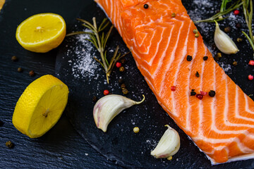 Raw fillet of salmon fish and spices on a slate board