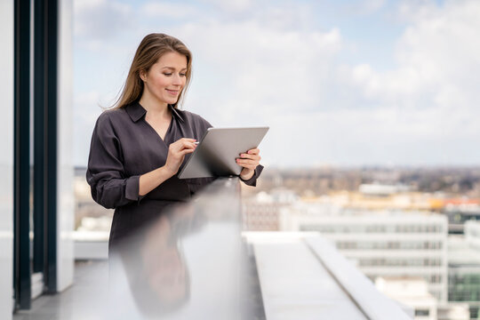 Smiling businesswoman using graphics tablet in balcony at office