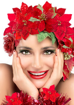Christmas beauty with smiling model girl wearing poinsettias. Christmas woman with holiday Hairstyle and Makeup