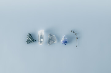 Minimalist flat lay of healing crystals: clear quartz, smoky quartz, amethyst, black tourmaline and...