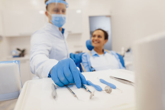 Dentist taking dental tools to provide treatment for client