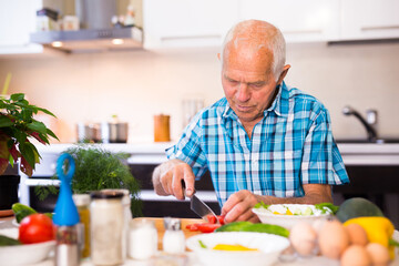 Fototapeta premium senor man preparing fresh vegetable salad at home in the kitchen
